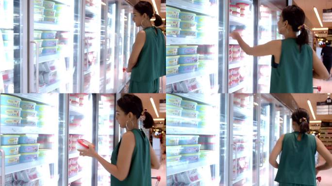 年轻漂亮的亚洲女人在杂货店超市的冰箱里挑选冰淇淋。