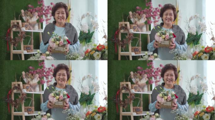 在插花课结束后，骄傲的亚洲中国高级女性拿着自己的花篮在花店里微笑着看着镜头