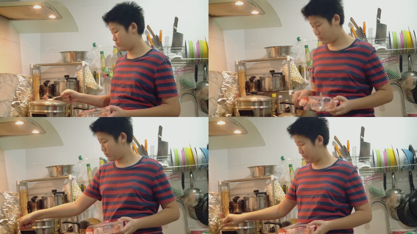 亚洲男孩在家里的厨房里用炉灶做饭，周末生活方式理念。