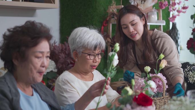 亚洲华人女花艺师在花店教成年学生插花