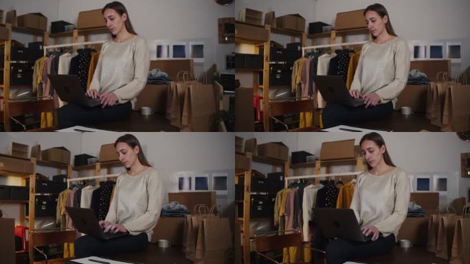一名年轻女子正在她的新网上服装店检查她的笔记本电脑