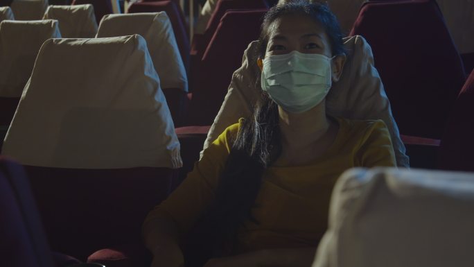 电影院里戴着防护面罩的微笑亚洲女人的肖像