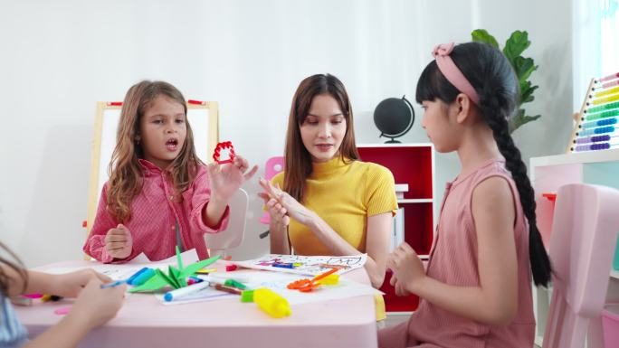 亚洲学龄前小女孩和老师一起学习，一起玩橡皮泥制作几何玩具，一起制作折纸鸟。
