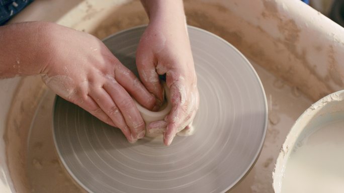 陶器课上塑造陶罐的双手特写。上图是一尊享受他最喜爱爱好的雕塑。放大技术娴熟的艺术家柔软、棕色、凌乱的