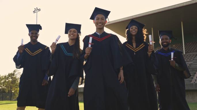 毕业日，一群学生举着证书站在大学操场上。年轻毕业生庆祝他们的成就和完成学业和教育