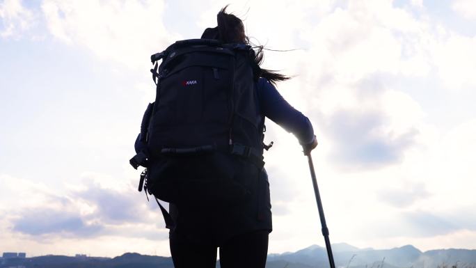 女孩背着背包正在登山爬山向着山顶徒步前进