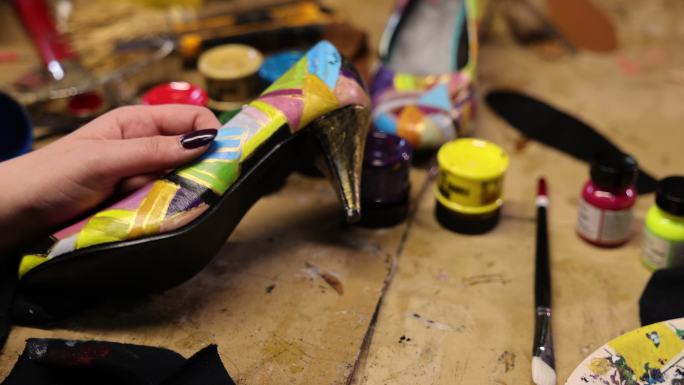 一位面目全非的女艺术家在车间工作时为高跟鞋作画