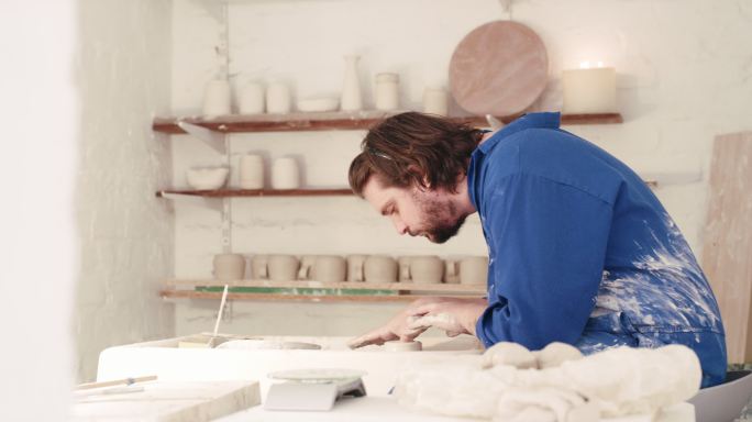 在一个陶瓷艺术工作室里，年轻的陶艺家用手在陶轮上制作一个粘土碗。艺术创意陶工造型，在业余作坊中用天赋