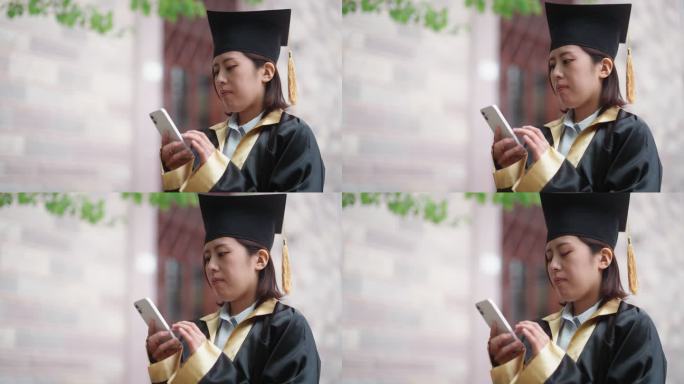 身穿毕业礼服的亚洲女大学生在校园里使用智能手机发短信
