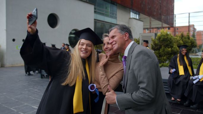 典礼结束后，美丽的女毕业生与骄傲的父母自拍