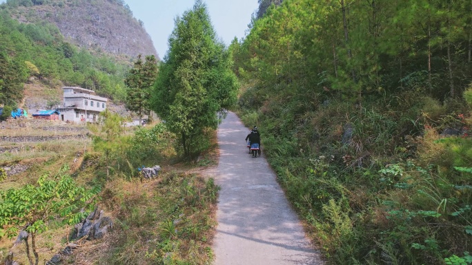 广西白裤瑶原住民山路骑摩托车和走路背影