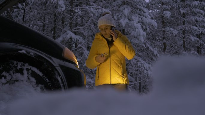 汽车在第一场雪中抛锚了。应急灯。天气不好时，汽车在偏僻的地方抛锚。汽车保险。一个女人在路上。