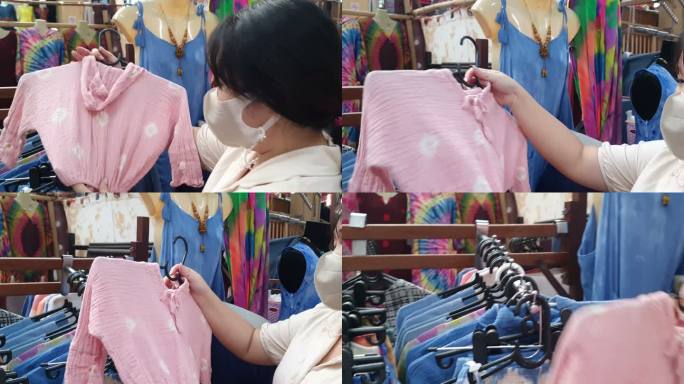 泰国清迈，戴着口罩的亚洲年轻女性在商店里挑选和购买衣服