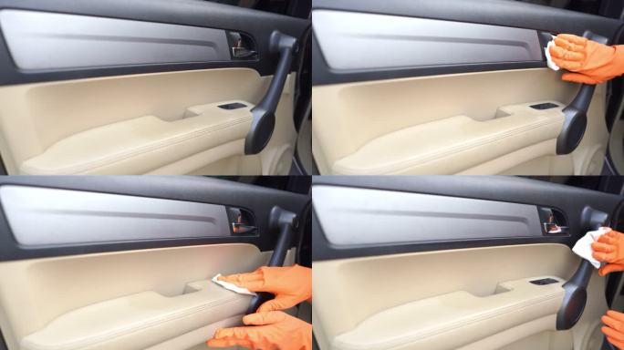 在家车库里，用手拿手套擦拭汽车内部清洁剂covid-19病毒的门把手表面。