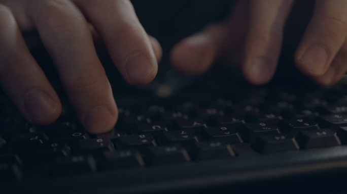 一名男子在黑色电脑键盘上打字