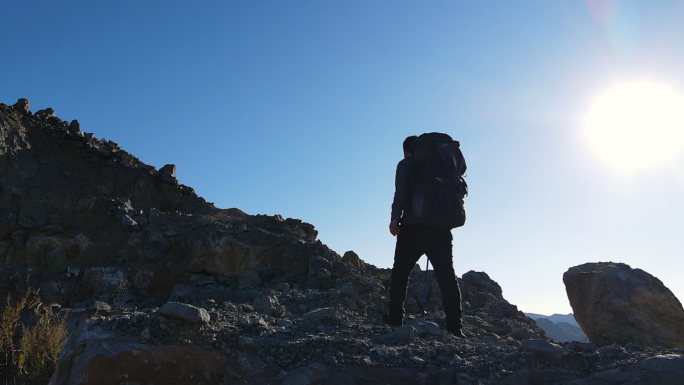 男人背着登山包爬上山顶攀登顶峰人物剪影