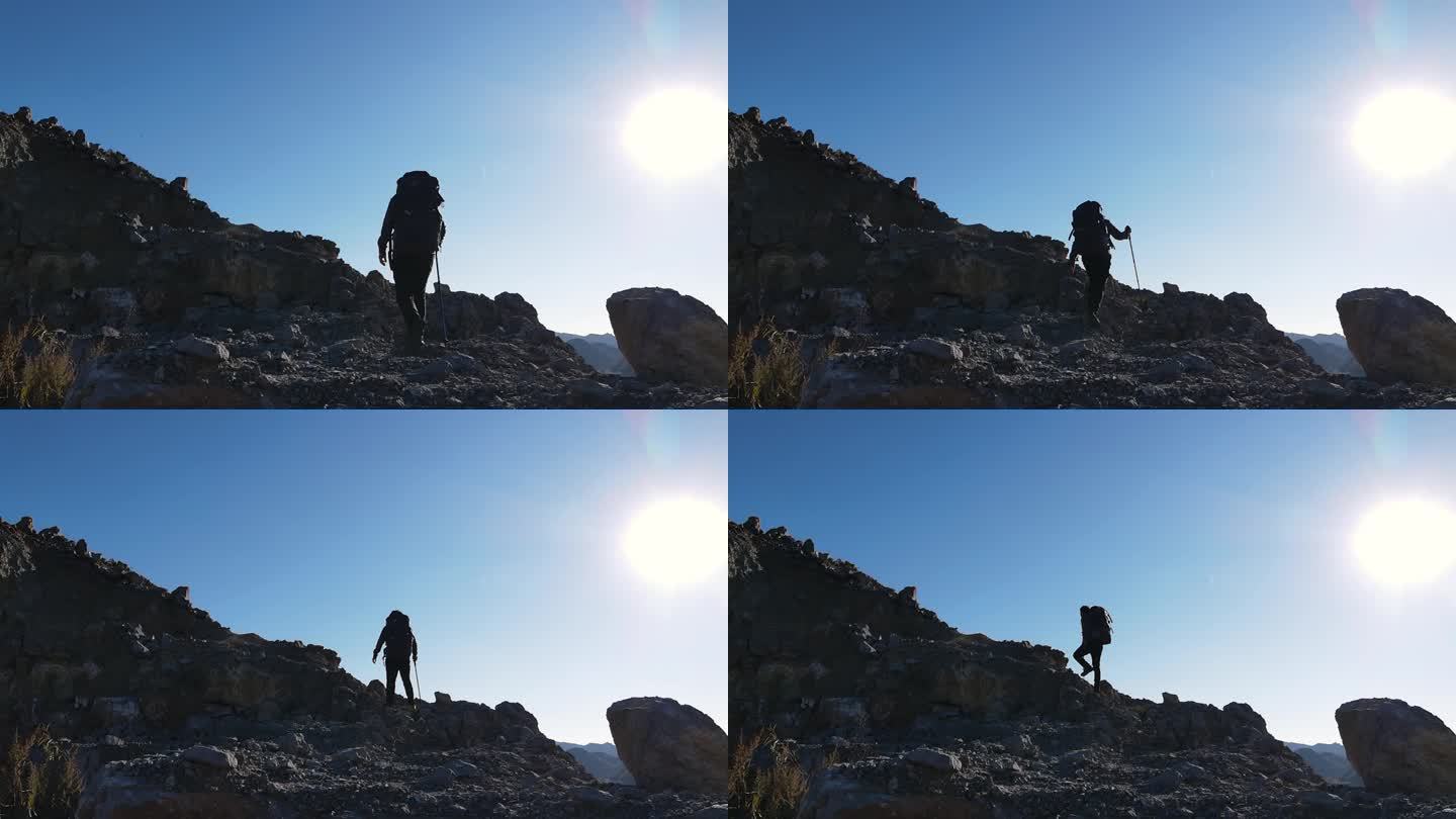男人背着登山包爬上山顶攀登顶峰人物剪影