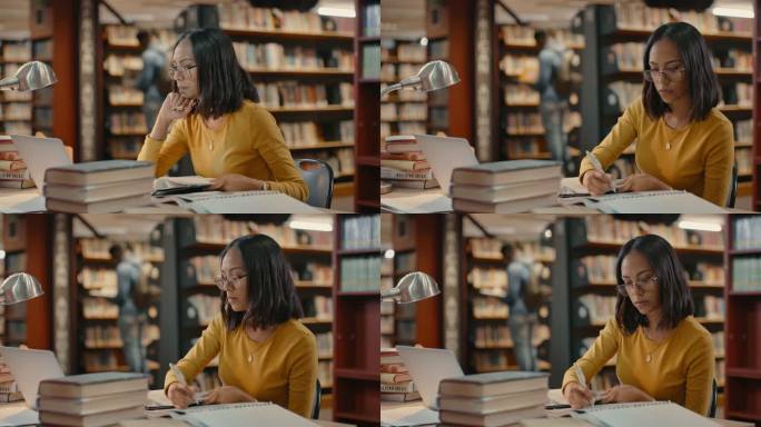 一名学生在校园图书馆学习考试或研究项目。一个戴着眼镜的快乐的年轻律师坐在书桌旁，手里拿着一堆书，一边