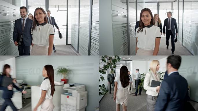 一位亚洲办公室员工走在办公室走廊上，结束电话，对着镜头微笑的照片