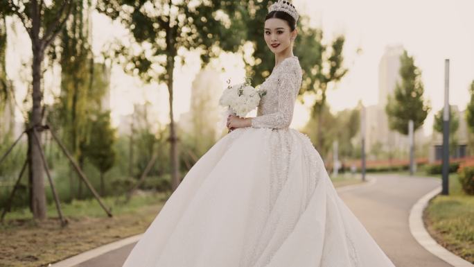 年轻漂亮的亚洲新娘穿着白色婚纱，在花园里散步，从背后拍摄，慢镜头