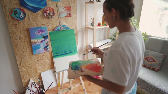 骄傲的女艺术家欣赏她在家创作的油画