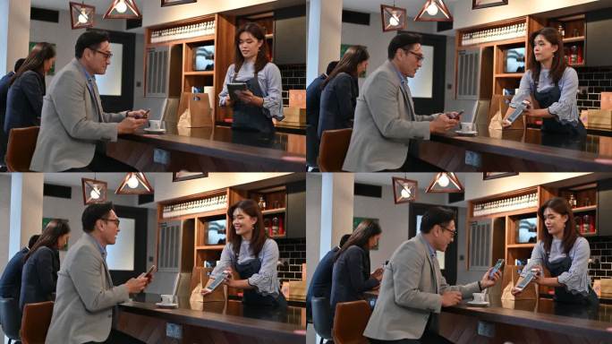 一位亚洲商人在咖啡店使用智能手机进行无接触支付