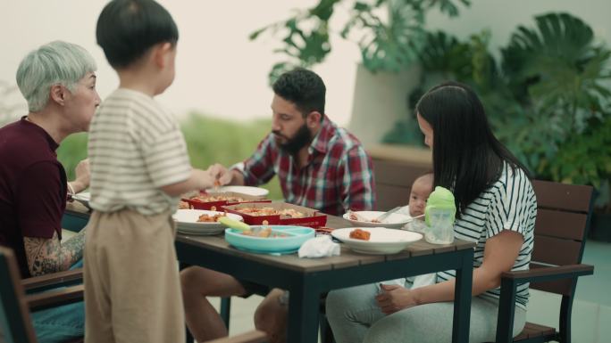 快乐的亚洲家庭在家里花园里吃户外大餐
