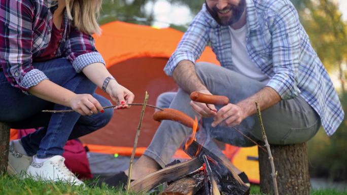 夫妇在篝火上烤香肠