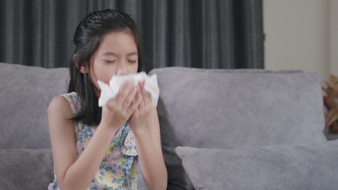 亚洲小孩打喷嚏，用餐巾擤鼻涕。她过敏。幼小的家里患流感的女孩