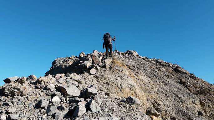 男人背着登山包爬山背影登上山顶攀登顶峰