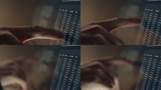 一名男子用手指在一台装有成排数据的电脑显示器上移动