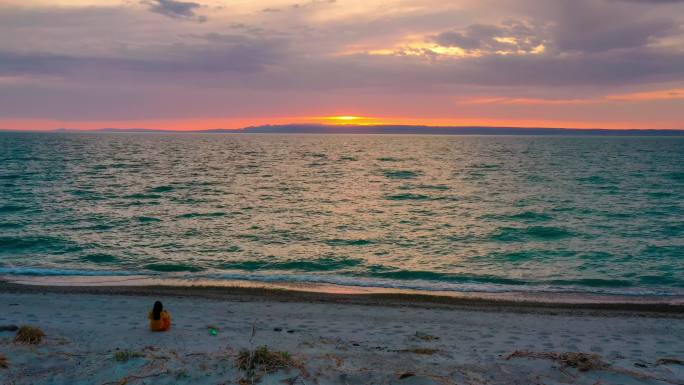 一个女人坐在海边看日落