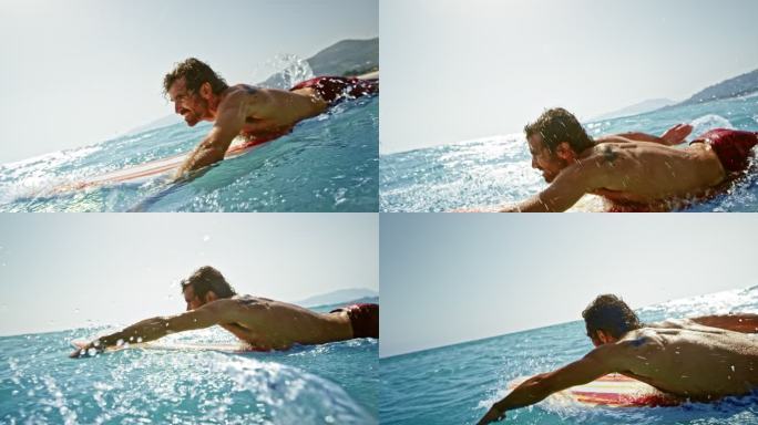 男冲浪运动员SLO MO在海洋中的冲浪板上划水