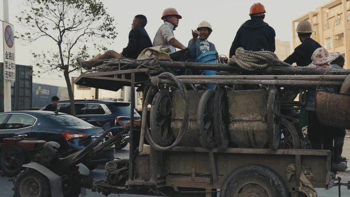 马路上的三轮车 车上坐着戴安全头盔的工人
