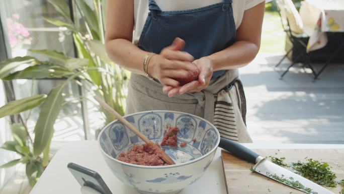 一位女士在厨房里为汉堡肉饼整形牛肉