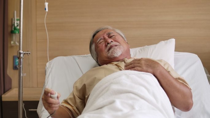 在医院病床上，一位老年男性患者按下紧急护士呼叫按钮。