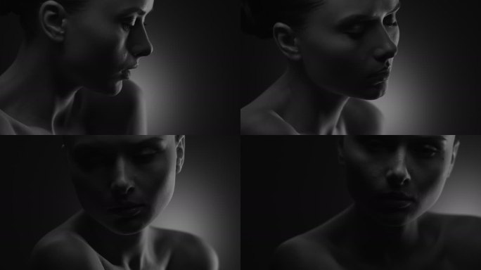 一个裸体女孩的脸部和肩膀的特写镜头，她慢慢地将它们从一个镜头移到另一个镜头。黑白视频。