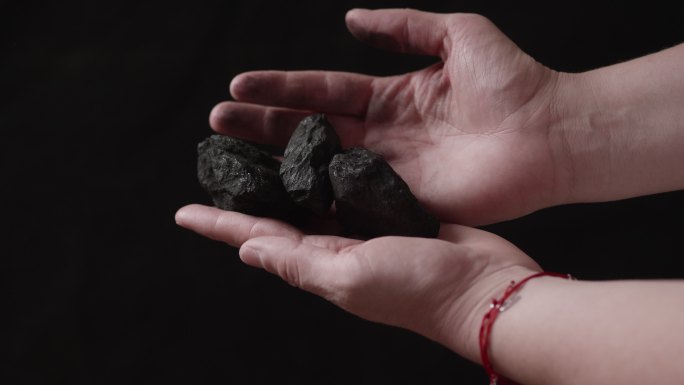 手上的煤块手中煤矿能源危机黑色背景