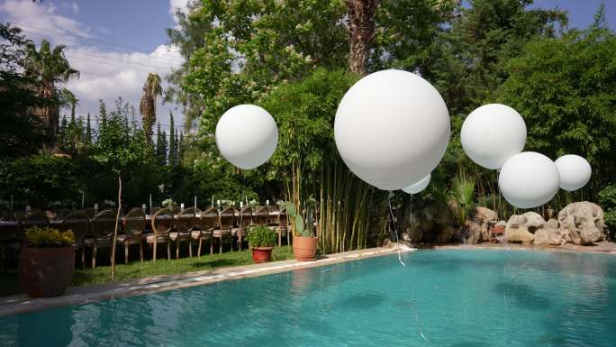 室外有白色大气球的游泳池。池畔派对。水上的气球。