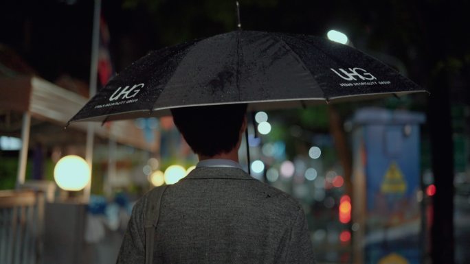 商人戴着防护面罩在雨中行走。