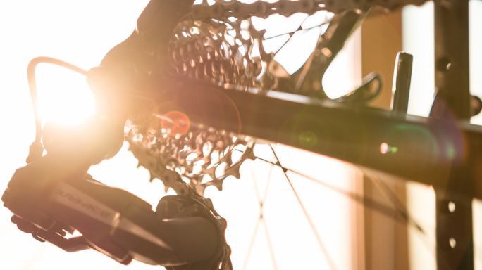 日落时的自行车车架细节、车轮轮辐、齿轮和链条
