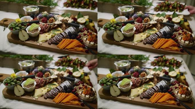 在室内庆典/派对上，一个人将开胃菜放在背景中，而摄像机将开胃菜与各种水果、酱汁和装饰一起放入桌子上的