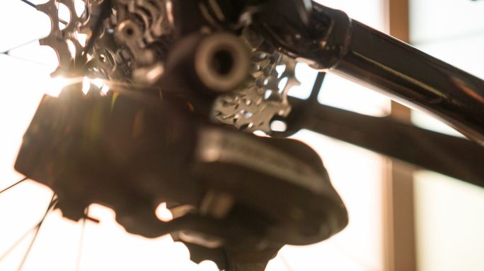 日落时的自行车车架细节、车轮轮辐、齿轮和链条
