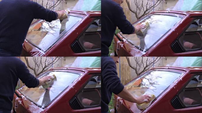 特写一名男子在后院拿着海绵洗车的双手。