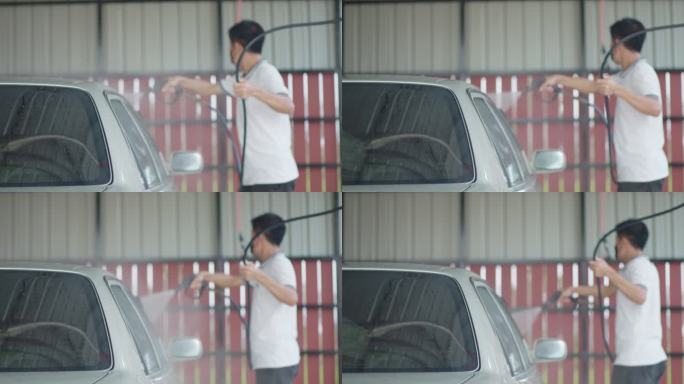 一名亚洲男子在家里用泵上的压力喷雾器洗车