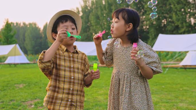 两个小孩在草地上吹泡泡