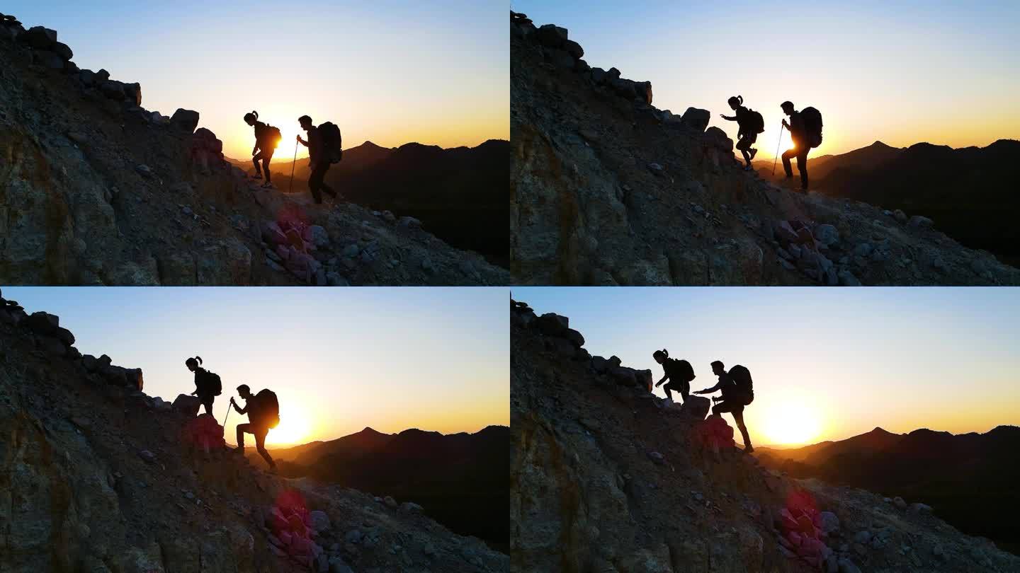 年轻夫妻户外探险登山剪影攀登顶峰爬山背影