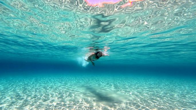 大海中的年轻女人海洋泳池清澈海底波纹比基
