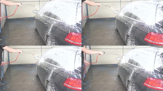 男性在洗车前用喷枪在车上喷洒雪沫