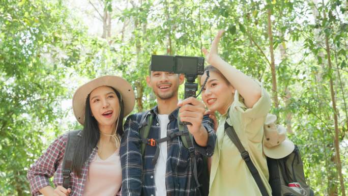 一群亚洲背包客独自在森林里旅行。有吸引力的朋友旅行者使用手机录制视频视频，在假期旅行中快乐地漫步在自